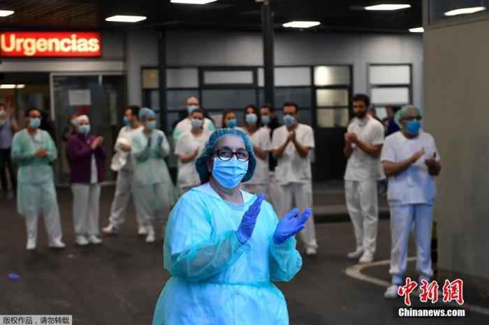 当地时间4月27日，在西班牙马德里的一家医院外，医护人员在为全国禁闭期间居家隔离的民众们鼓掌欢呼，为他们加油打气。